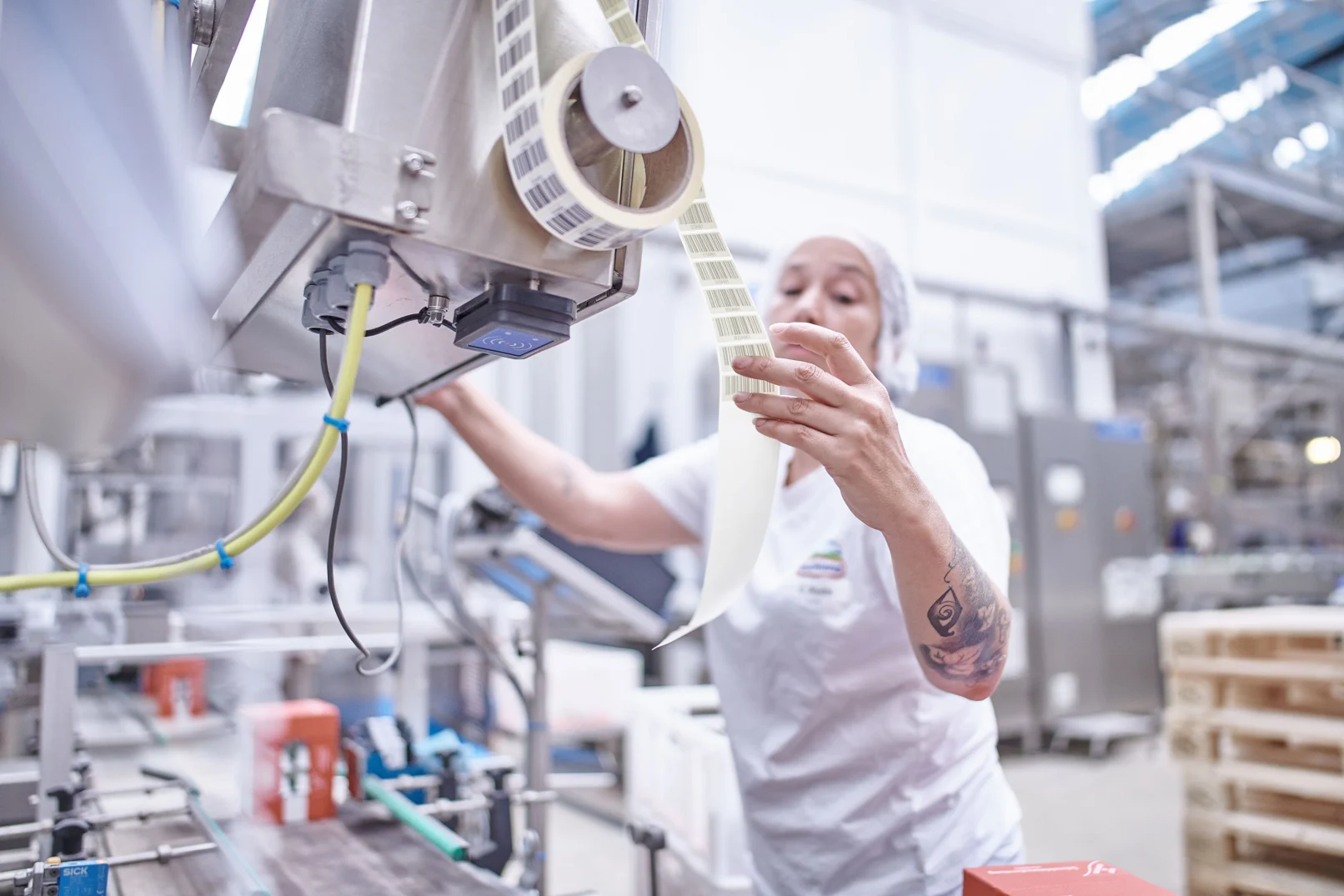 Mitarbeiterin von Hochland kontrolliert Etiketten an einer Verpackungsmaschine