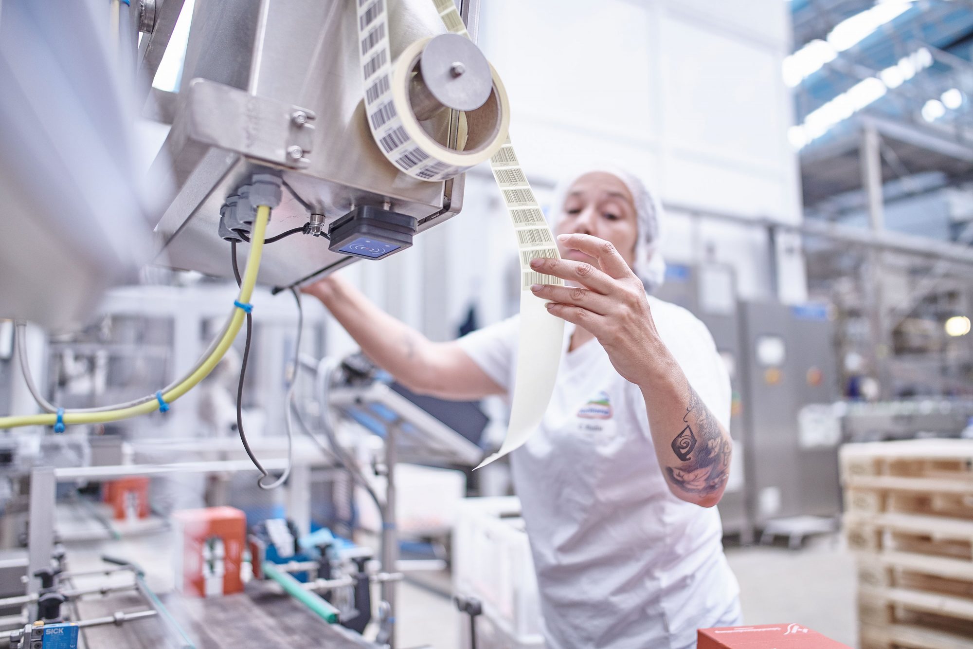 Mitarbeiterin von Hochland kontrolliert Etiketten an einer Verpackungsmaschine