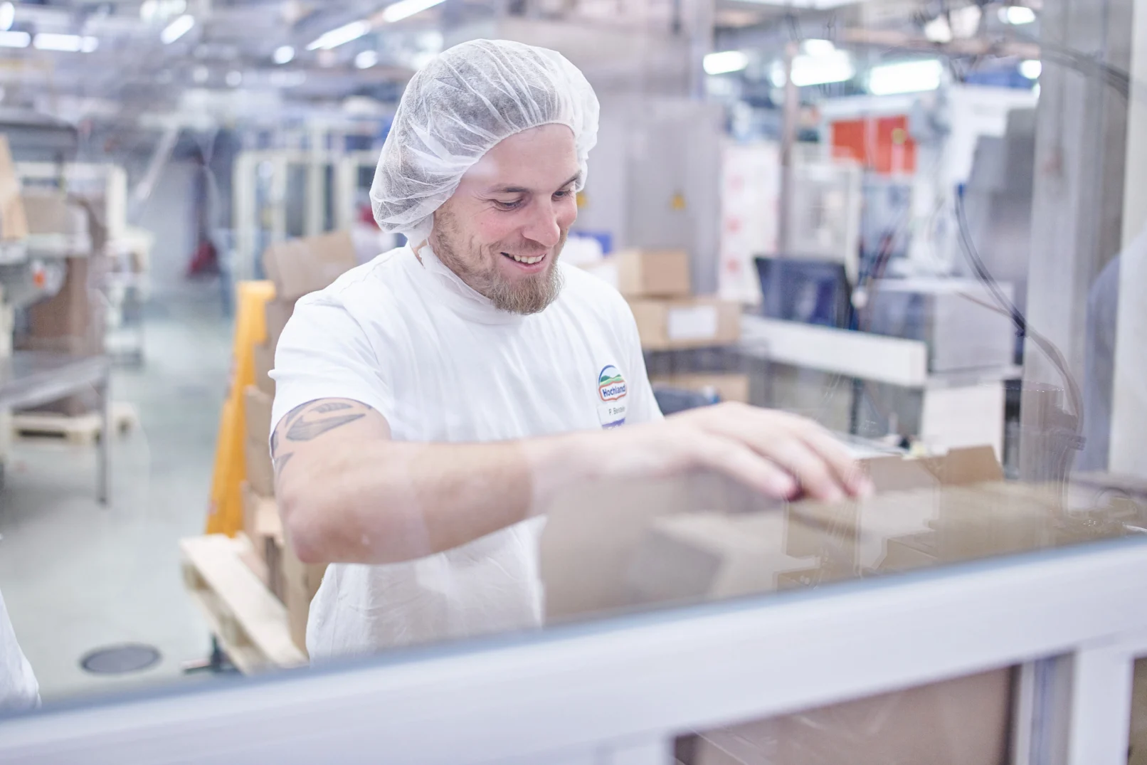 Mitarbeiter von Hochland verpackt Kartons in der Käseproduktion, Teil einer Corporate-Fotoreportage in Schongau und Heimenkirch im Allgäu
