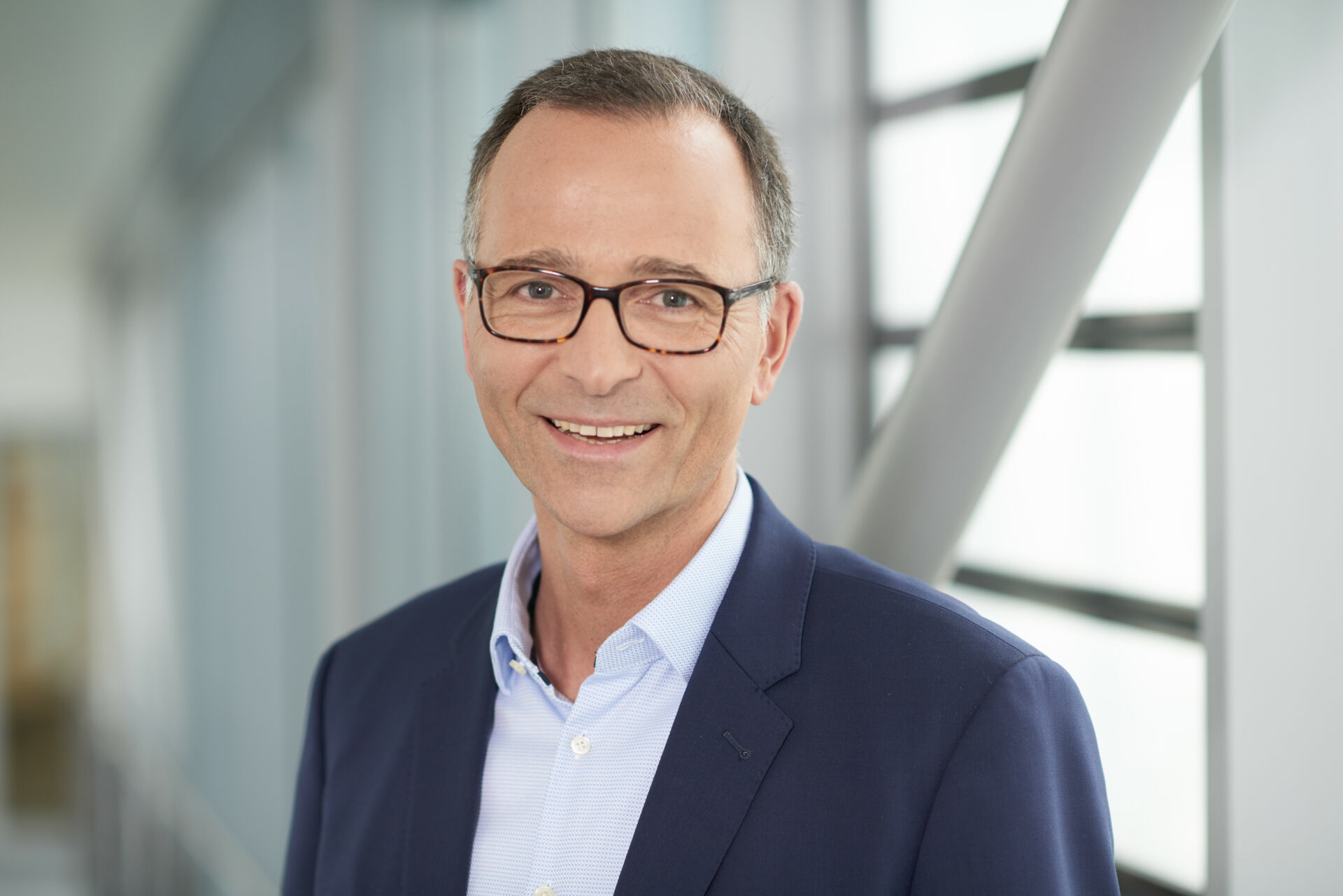 Portrait des damaligen Geschäftsführers und heutigen Vorstands Josef Stitzl mit Brille und dunkelblauem Sakko