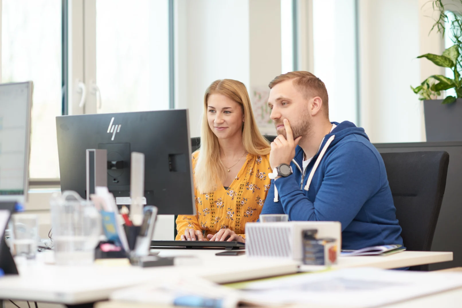 Zwei Hochland-Mitarbeitende arbeiten gemeinsam an einem Computer