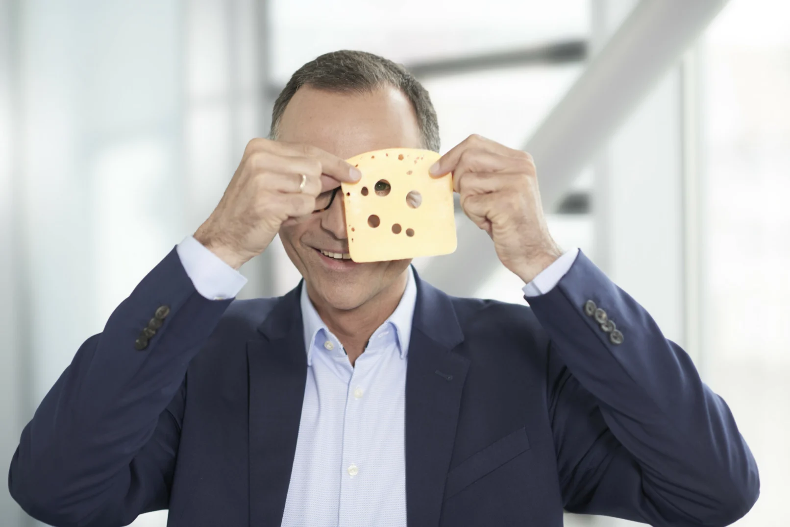 Hochland-Führungskraft hält eine Käsescheibe spielerisch vor das Gesicht