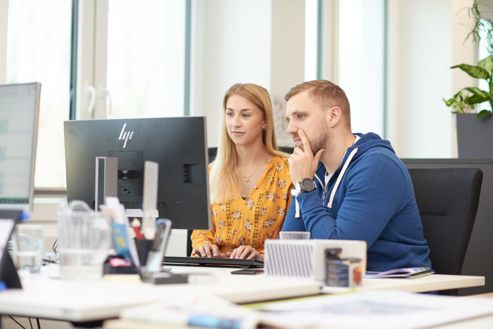 Zwei Hochland-Mitarbeitende arbeiten gemeinsam an einem Computer
