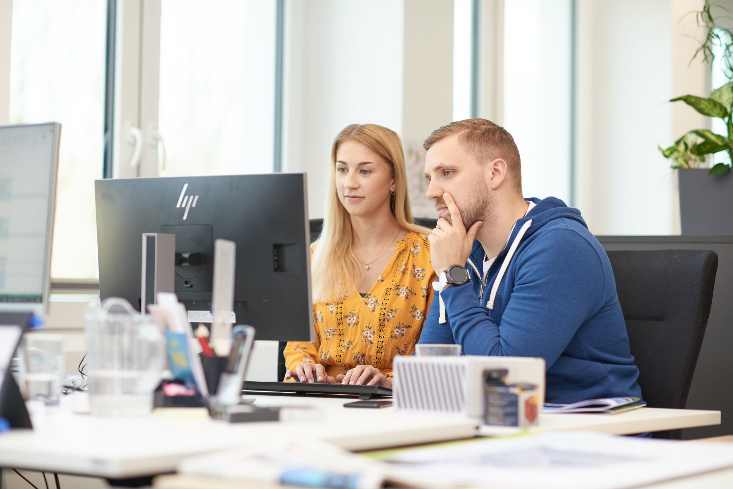 Zwei Hochland-Mitarbeitende arbeiten gemeinsam an einem Computer