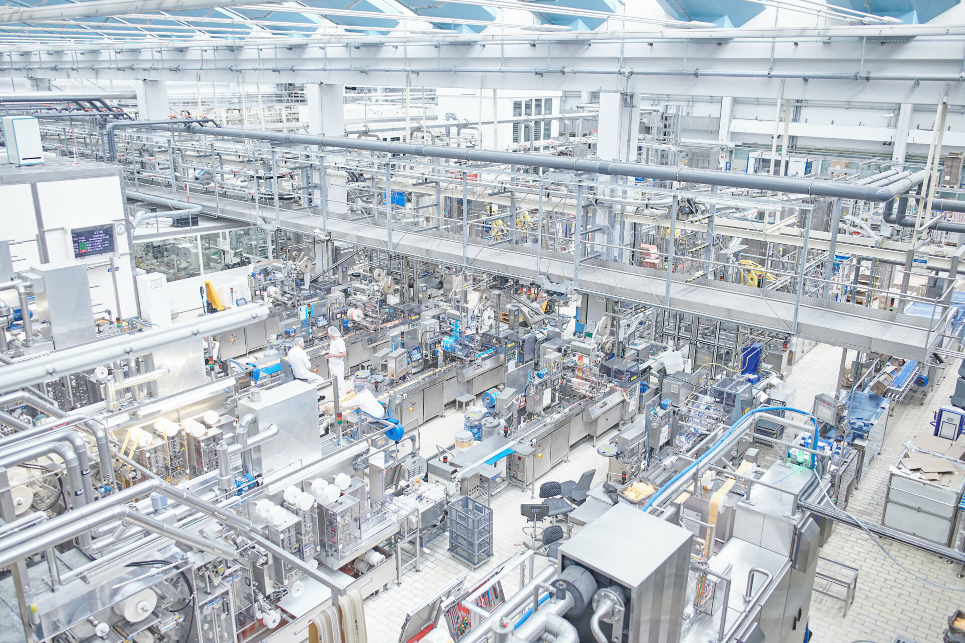 Weite Sicht auf Produktionsbereich mit Verpackungsanlagen und Mitarbeitenden bei Hochland