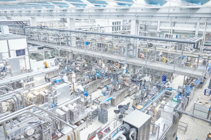 Produktionsbereich mit Verpackungsanlagen und Mitarbeitenden bei Hochland
