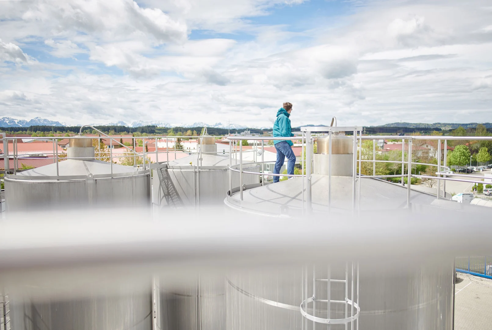 Mitarbeiter auf den Milchtanks am Hochland-Standort Schongau vor Alpenpanorama
