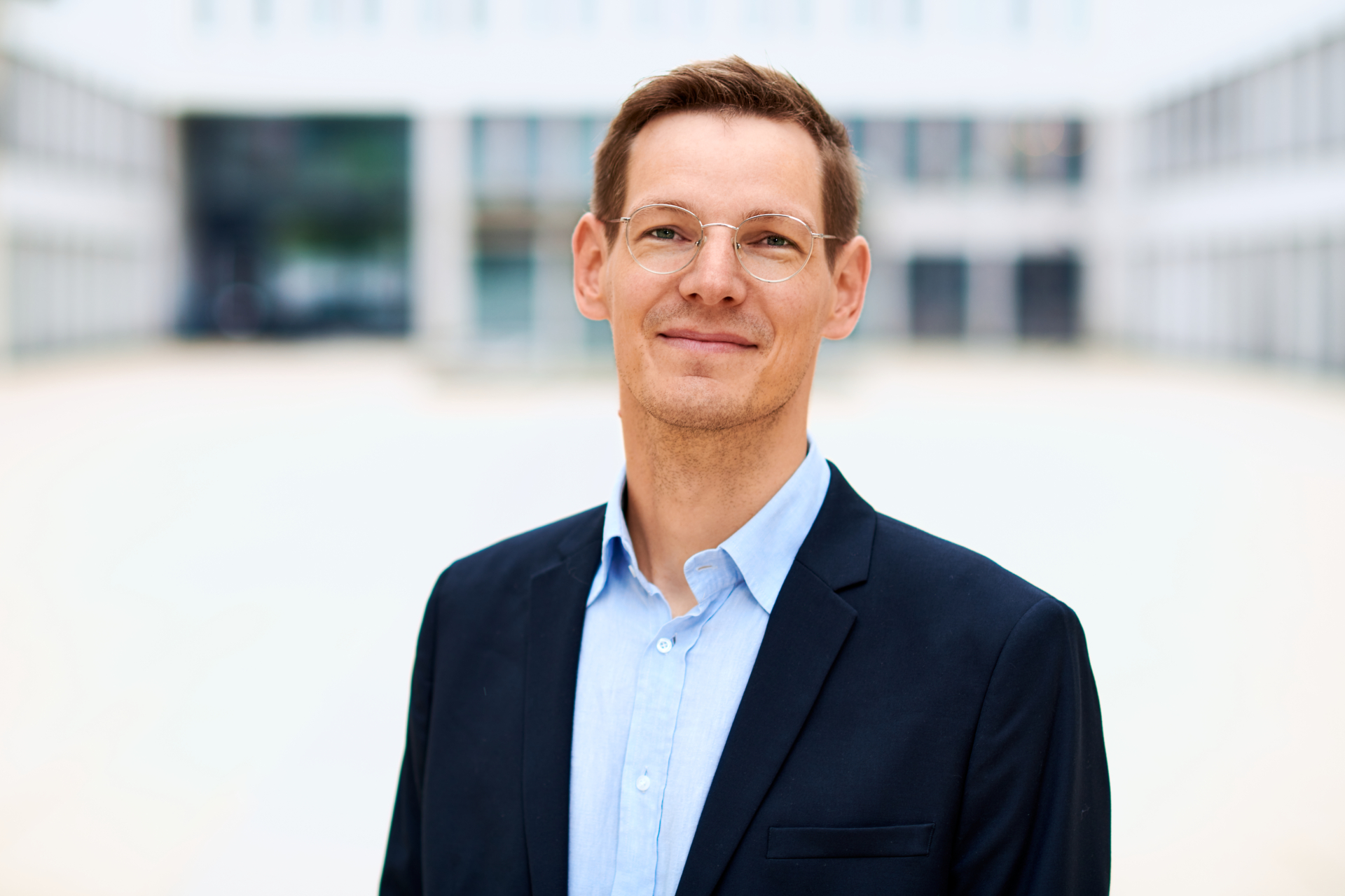 Lächelndes Porträt von David Klötzer vor moderner Bürofassade