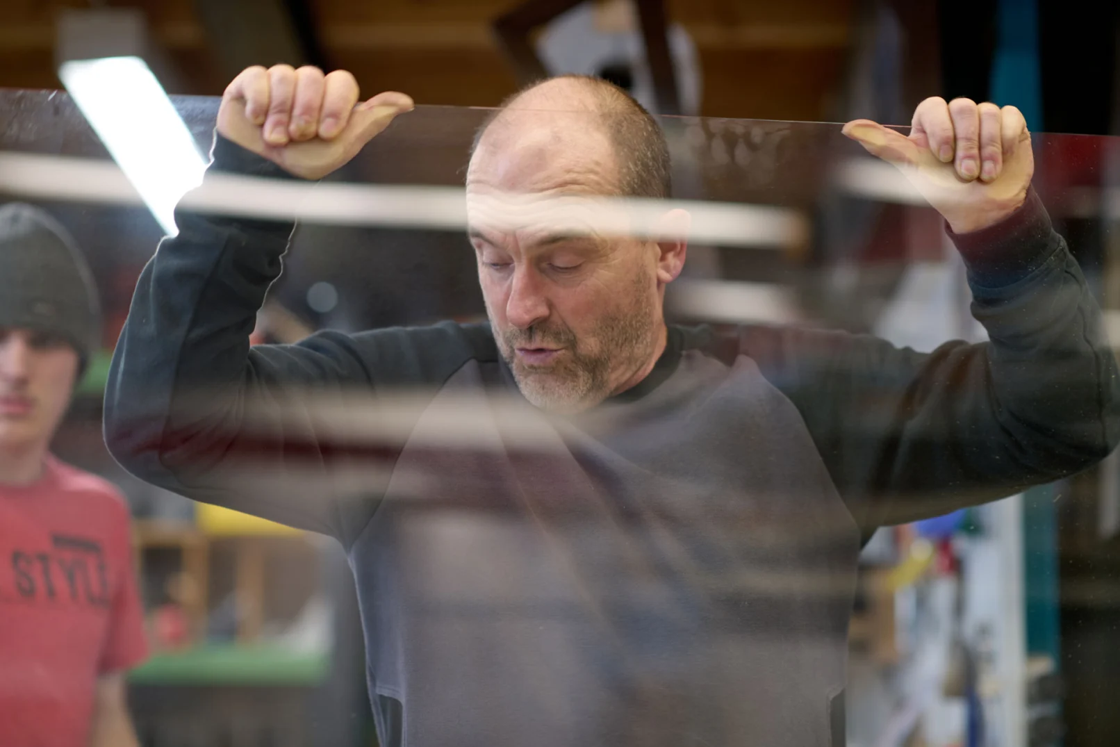 Fensterbauer hebt eine große Glasscheibe in der Werkstatt