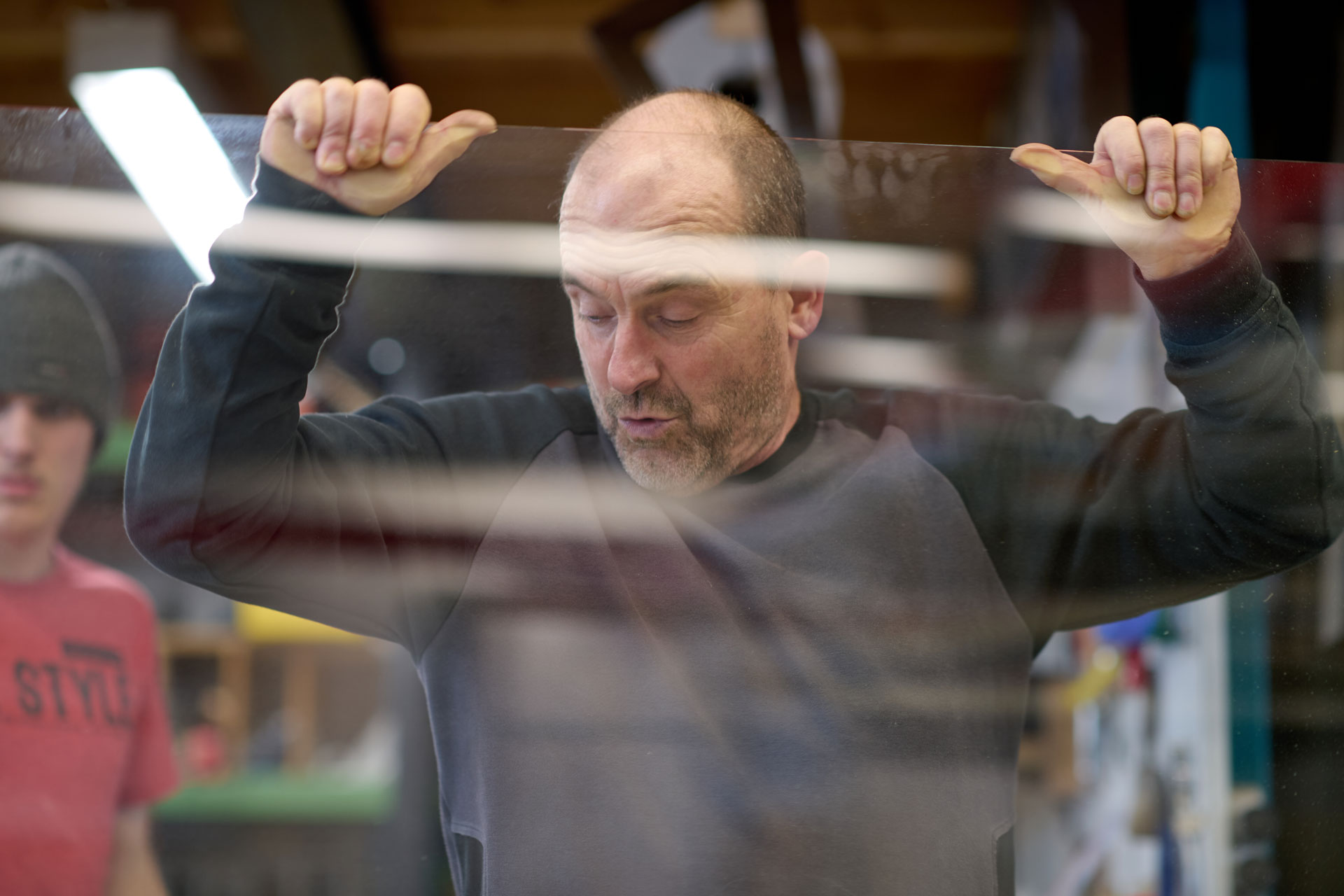 Fensterbauer hebt eine große Glasscheibe in der Werkstatt