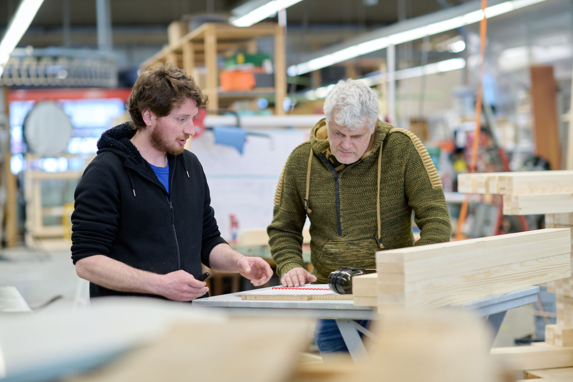 Zwei Fensterbauer besprechen ein Bauteil in der Werkstatt
