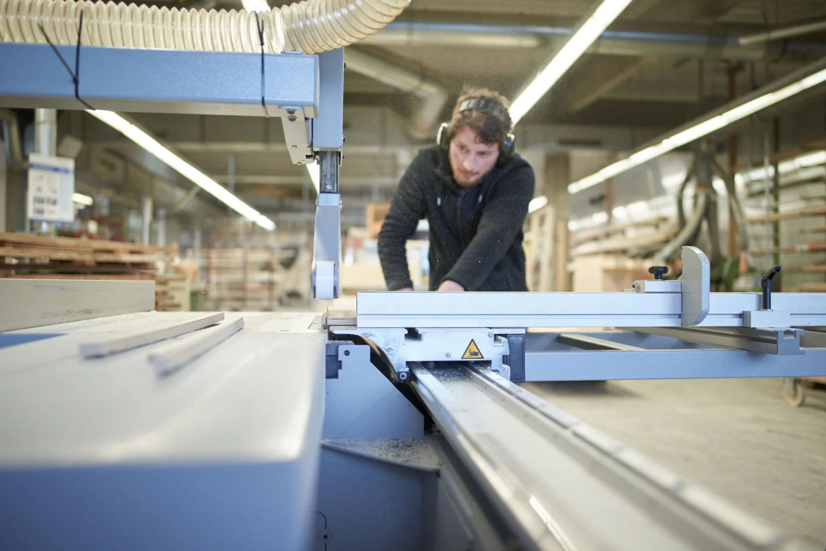 Mitarbeiter bearbeitet ein Bauteil an einer Maschine in der Fensterbau-Werkstatt in Isny im Allgäu