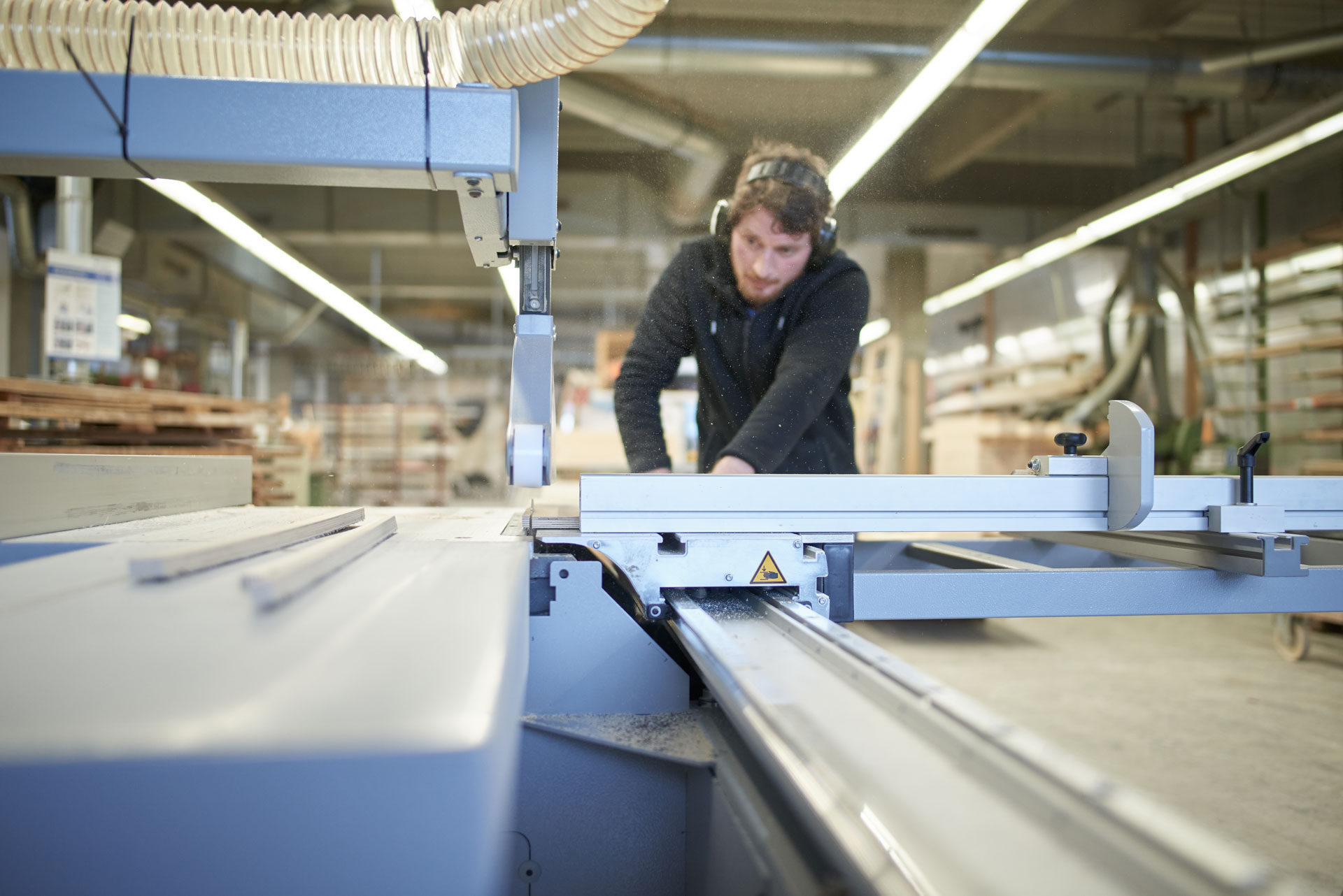 Mitarbeiter bearbeitet ein Bauteil an einer Maschine in der Fensterbau-Werkstatt